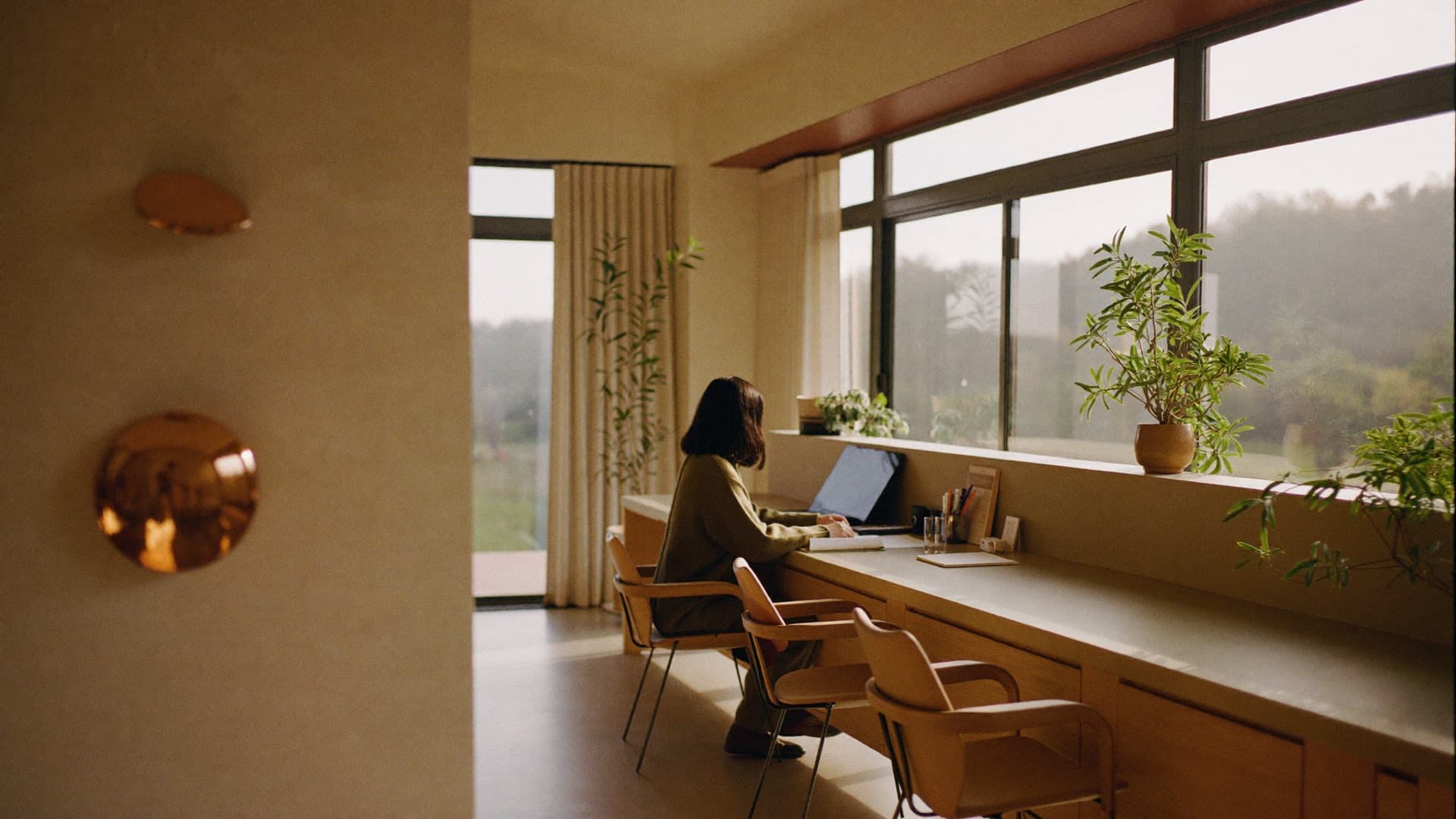 A sunlit desk in a warm clinic interior, a figure at work by the window